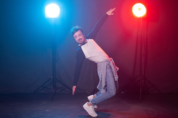 Fototapeta na wymiar Dance, hip-hop and reggaeton concept - young man dancing over the lights.