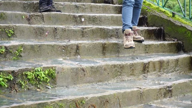 Slow motion shot of indian women climbing down stairs with trekking and sport shoes on a mountain trek with lush green backgrounds