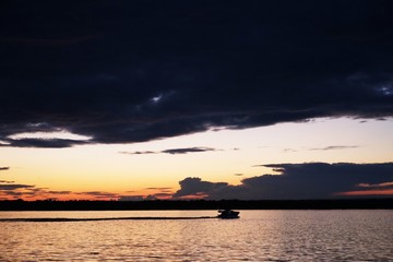 Sunset across the river at Samara, Russia, sport boat on the background