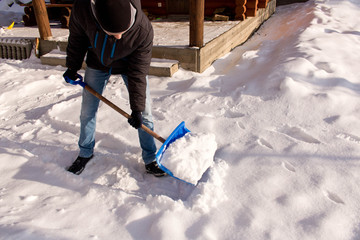 A teenager shoveling snow in his yard. The concept of a snowy winter.