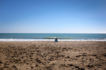 lonely woman on a beach contemplating the blue sea