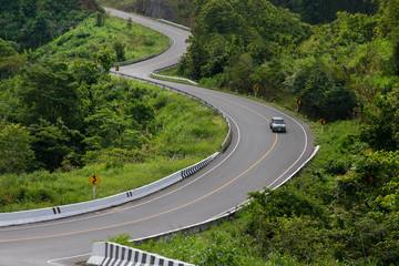 Curved asphalt road with a car in the mountains.