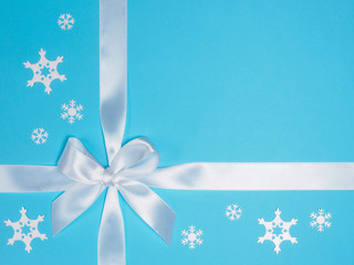 White bow and snowflakes on a blue background. Winter Holidays Concept