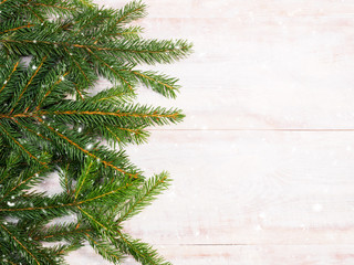 Christmas background with fir branches and snowflakes on brown wooden background. Winter holidays concept