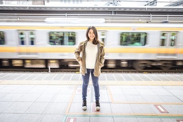 Naklejka premium Portrait woman standing and smiling in subway. Speed electric train on a platform in metro.