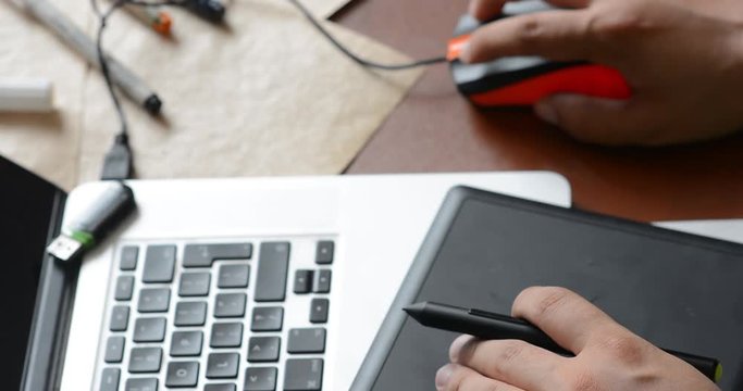 Close-up of the hands of an ambidexter designer who works equally well with his right and left hands while working with a mouse and a graphic tablet.