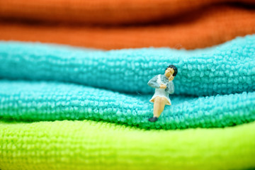 Miniature people :  Housewife sitting on the folded towel.