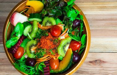 Closeup top view various fresh healthy mixed vegetables salad with flyinh fish roe on top in wooden bowl.