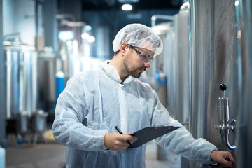 Shot of caucasian male technologist expert operating production machine in food factory and doing...