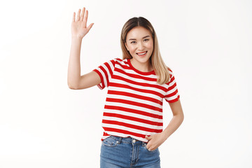 Obraz na płótnie Canvas Hey friends how hanging. Friendly outgoing sociable cute asian blond girl raise hand waving palm hi hello gesture smiling broadly happy introduce herself new members, standing white background