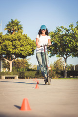 Woman, dressed in broken jeans, riding electric kick scooter