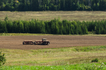 Naklejka premium tractor cultivates field, agriculture in countryside