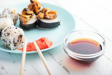 Sushi rolls in blue plate, chopsticks and soy sauce