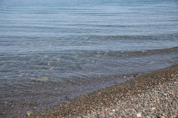 Wet stones on the sea shore. transparent waves with foam, on a warm