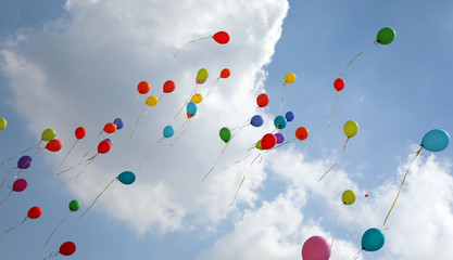colored balloons fly into the sky with clouds during the party