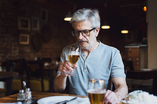 Senior man having a beer in the bar - Powered by Adobe