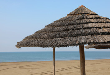 huge straw umbrella in the sunny deserted beach