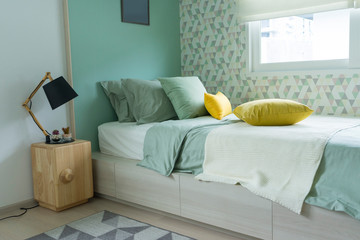 Contemporary teen bedroom with green pillow and modern side table lamp. 