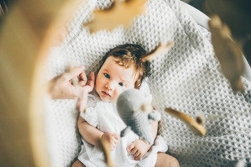 Funny two month old baby girl lying on the bed. Mother stroking daughter. High angle view of...