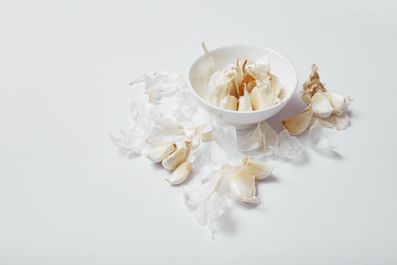 Garlic bulb, cloves and peel on white background, top view with copy space