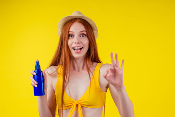 amazed redhaired ginger woman holding two plastic bottle of suncream,facial expression 