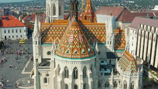 Budapest, Hungary - 4K drone flying away from the beautiful roof of Matthias Church in front of the Fisherman's Bastion at the heart of Buda's Castle District on a bright summer day