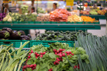 Cucumbers, eggplants, radish and spring onions on the fruits and vegetables aisle in a store.