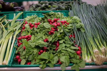 Radish and spring onions on the fruits and vegetables aisle in a store.