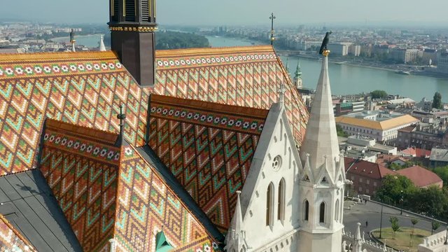 Budapest, Hungary - 4K drone flying sideways of the beautiful Matthias Church in front of the Fisherman's Bastion at the heart of Buda's Castle District on a bright summer day with Parliament