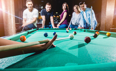 Group of young cheerful friends playing billiards.