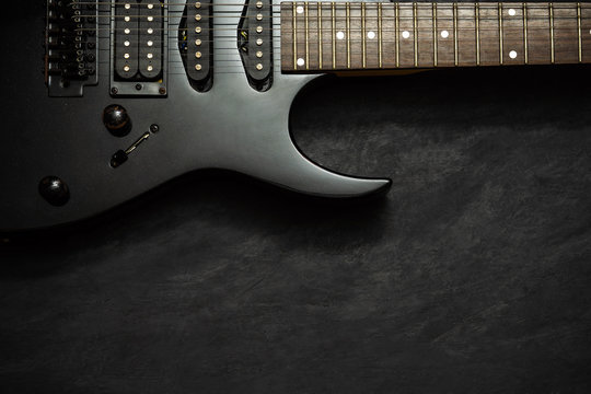 Black electric guitar on black cement floor. Top view and copy space for text. Concept of rock music.