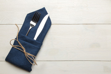 table setting. cutlery. Fork, knife in a blue napkin on a white wooden table. top view - Powered by Adobe