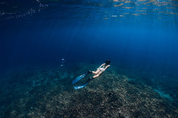 Fototapeta na wymiar Woman freediver with fins glides underwater in ocean