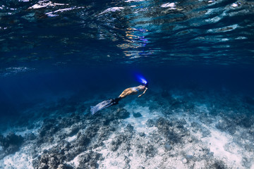 Woman freediver with fins glides underwater in ocean