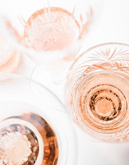 Sparkling rose wine in different glasses on white background