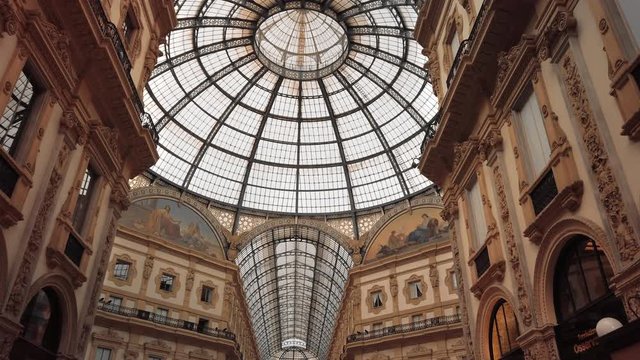 Milan, Italy - May 2019: Glass dome and interior gallery Vittorio Emanuele. The concept of shopping and expensive luxury stores. Slow motion, dolly shot.