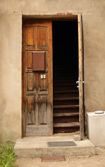 Fototapeta na wymiar Aged dark wooden door in weathered concrete wall