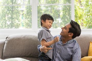 Happy son playing with father in living room. Asian family portrait concept