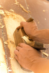 Wooden hand plane. Closeup of woodworker's hands shaving with a plane in a joinery workshop
