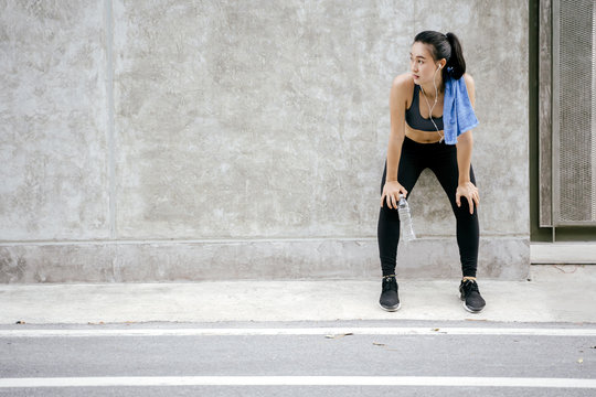 Young asian woman runner resting after workout running in street city road. © saksit