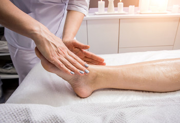 Obraz na płótnie Canvas Beautiful young woman enjoying foot massage in spa salon. Cosmetology