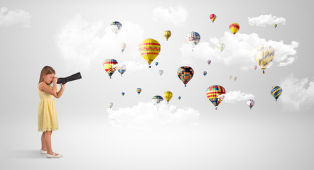 Cute girl looking to air balloons through a telescope