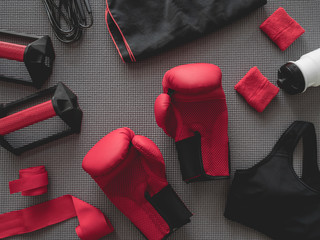 top view of boxing gym concept with boxing glove, Gym Outfit, skipping rope and accessories on yoga mat background.