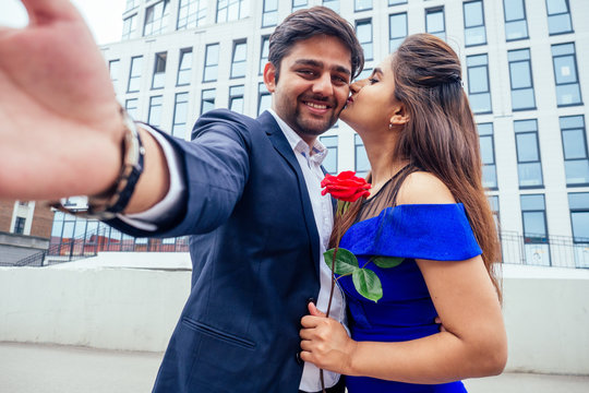 happy asian man in stylish black suit making selfie photo with his beautiful woman after proposal and giving gold ring on the background of the restaurant street downtown business center office
