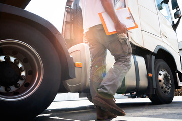 truck driver hand holding clipboard inspecting safety daily check around of a semi truck.