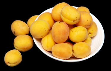Ripe apricot in a white plate on a black background