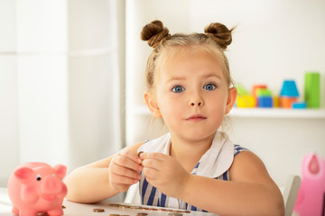 Cute little girl dreams with a piggy bank.