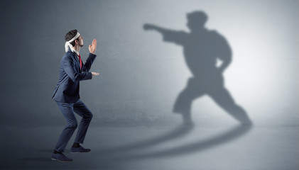 Businessman fighting with his strong karate man shadow