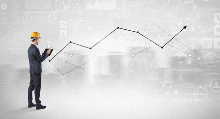 Engineer with construction helmet holding a plan and standing with graphs, charts and reports on the background