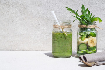 Vegetable smoothies and sliced ingredients cucumber, banana, paprika in two jars